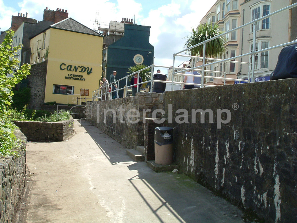 A sturdy Interclamp tube clamp handrail installed along a seaside town's boardwalk, providing safety and support.